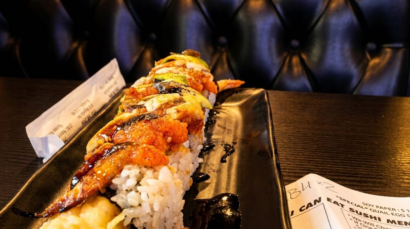 Eel and avocado sushi roll with roe drizzled with sauce